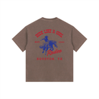Back view of a Coffee Brown Heavyweight Boxy T-Shirt with a red and blue Houston TX Rodeo "Ride Like A Girl" graphic.